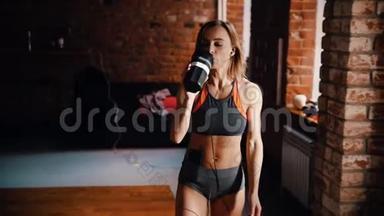 一位女运动员在健身房训练后喝水